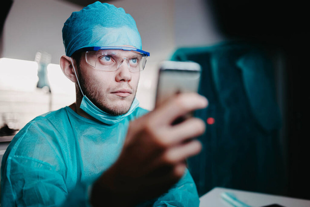 Άντρας χειρουργός γιατρός σκέφτεται πάνω από μια εργασία στο εσωτερικό της κλινικής, ιατρική έννοια - Φωτογραφία, εικόνα