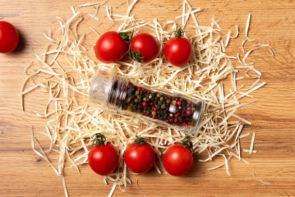 container with peppercorns and fresh tomatoes on wooden table  - Valokuva, kuva
