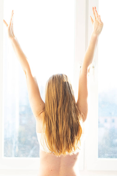 visszapillantás fiatal nő áll ablak közelében reggel - Fotó, kép