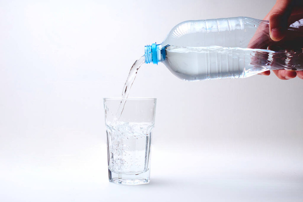 rajattu kuva henkilöstä kaatamassa vettä pullosta lasiin  - Valokuva, kuva