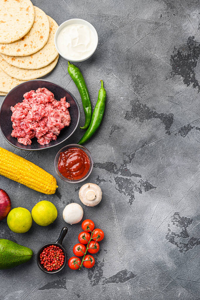 Zutaten für Rindfleisch mexikanische Tacos, Maistortillas, Chilipfeffer, Avocado, Fleisch auf texturiertem grauen Hintergrund, Draufsicht vertikal mit Platz für Text - Foto, Bild