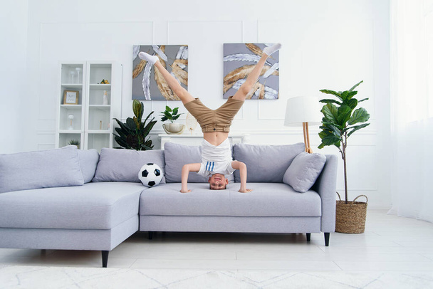 Adorable child standing on his head on sofa at home stock photo - Photo, Image