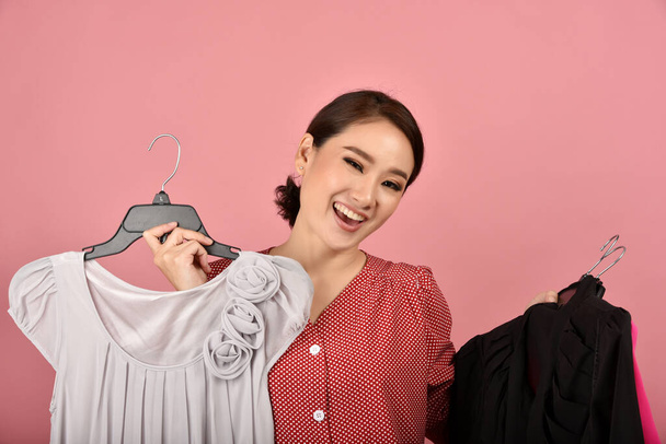 Lächelnd asiatische Frau genießen Sie den Einkauf Kleidung im Studio Schuss, Was Auswahl für die richtige Kleidung tragen. Werbeaktion für Modeeinkäufe. - Foto, Bild