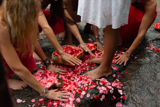 фото групи дівчат, що поклоняються ногам дівчини своїми руками палички з червоних квітів, які впали на землю
 - Фото, зображення