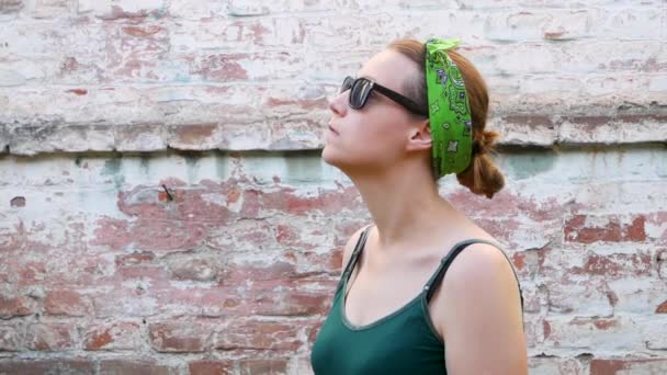 Woman with pollen allergy symptom smelling air with nose standing on brick wall background. Young sick girl sneezing, blowing her nose into handkerchief, using nasal spray against allergic rhinitis. - Footage, Video