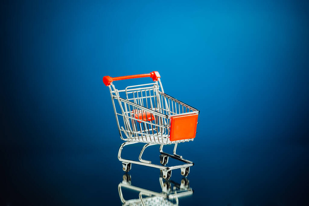 empty shopping cart, blue background - Photo, Image