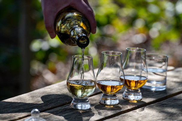 Verkostung von Scotch Single Malt Whisky von der Insel Islay, am intensivsten aromatisiert von allen Whiskys in Schottland auf altem Gartentisch an sonnigen Tagen - Foto, Bild