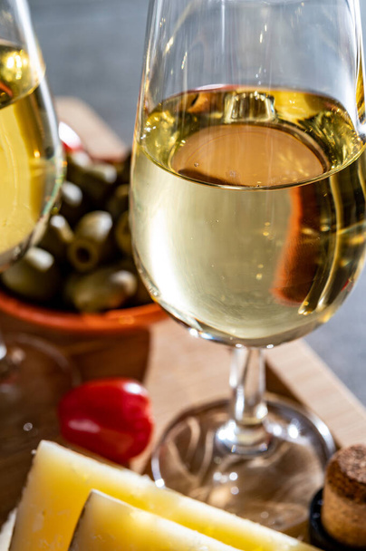 Ποτήρια από ξηρό κρύο κρασί σέρι φίνο σερβίρεται με ισπανικά τάπας, τυρί manchego, πράσινες ελιές, κρακεράκια τυρί - Φωτογραφία, εικόνα