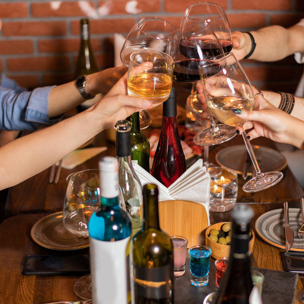Ludzie brzęczący kieliszkami wina na imprezie, przekąski na stole - Zdjęcie, obraz