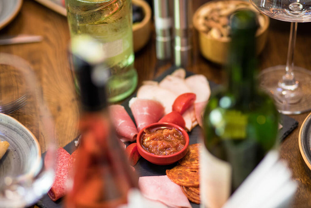 Leckere Wurst mit Tomaten und Sauce mit Weinflaschen - Foto, Bild