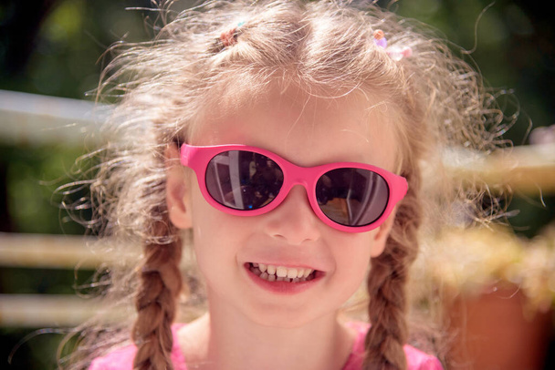 portrait of little Caucasian girl with sunglasses on green background - Foto, Imagen