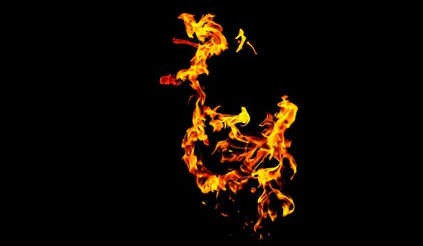Fire flames on black background isolated. Burning gas or gasoline burns with fire and flames. Flaming burning sparks close-up, fire patterns. Infernal glow of fire in the dark with copy-space - 写真・画像
