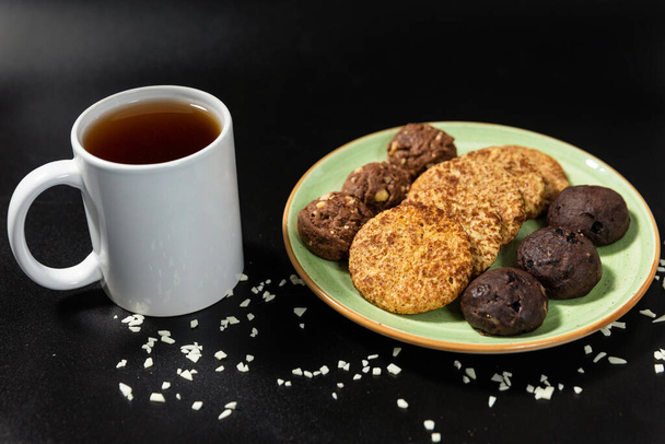 Gustosi biscotti al cioccolato con una tazza di tè sullo sfondo nero - Foto, immagini