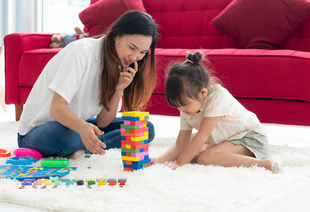 asian mother teaching her young daughter to play puzzles at home. homeschooling and family together concept - Fotoğraf, Görsel