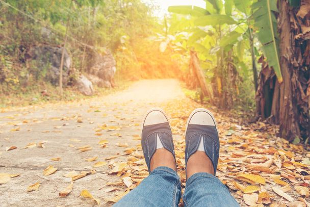 Hiking shoes young woman traveler sit down on summer park.focus on blue sneaker shoes and jeans on pathway. active activity vacation on hike mountain resting with walking way. Young traveler concept. - Photo, Image