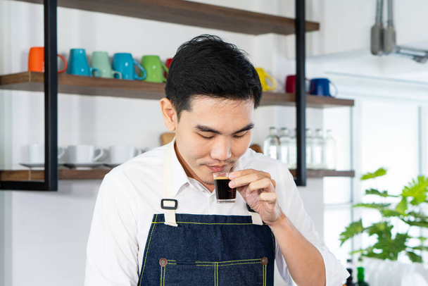 jeune homme asiatique beau jouit de l'odeur du café chaud dans le café. concept de barista et café - Photo, image