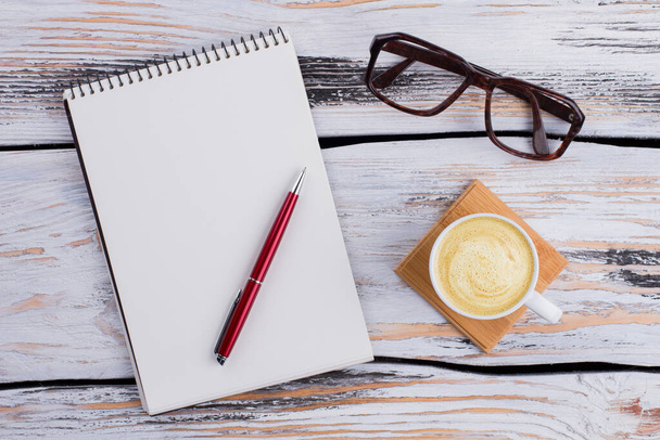 Bloc de notas en blanco con bolígrafo y gafas de sol en madera blanca
. - Foto, imagen