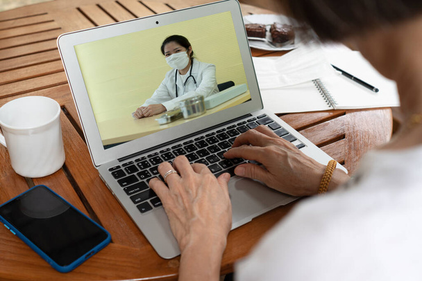 senior asiatique femme qui a des problèmes de santé en utilisant l'ordinateur pour consulter un médecin par vidéoconférence. santé et concept médical - Photo, image