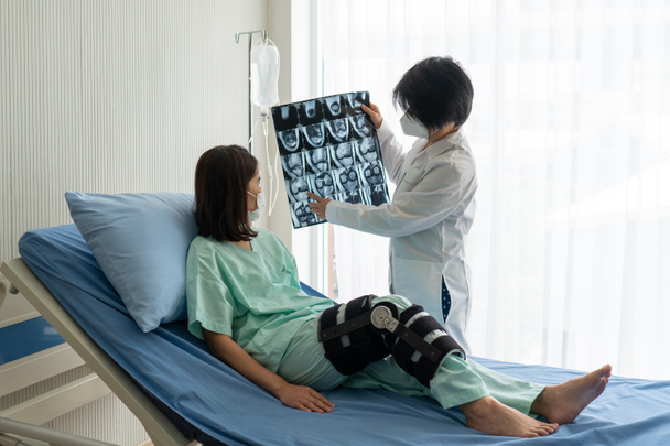 ortopedista mostra ressonância magnética ou ressonância magnética de joelho para paciente asiático que apresenta lesão de joelho por trauma esportivo. conceito médico e de cuidados de saúde
 - Foto, Imagem