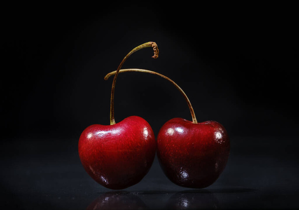 Two ripe juicy cherries on a black background - Φωτογραφία, εικόνα