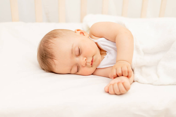 Small baby girl 6 months old sleeping in a white bed, healthy baby sleep. - Valokuva, kuva