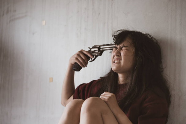 Ženy ve stresu drží zbraň namířenou na její hlavu způsobenou sociálními problémy, konceptem drog a zločinu - Fotografie, Obrázek