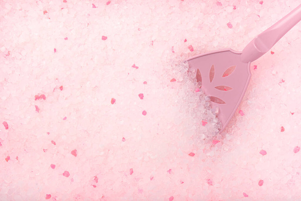 Detailní záběr na výplň kočičích odpadků. Růžové a bílé granule jsou krystaly, do kterých je vložena lopatka. Koncept článků o hygieně zvířat. Krásná textura. - Fotografie, Obrázek