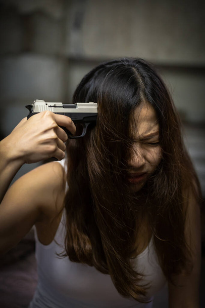Стрессовая женщина с пистолетом, направленным ей в голову, вызванная социальными проблемами, понятиями наркотиков и преступлений. - Фото, изображение