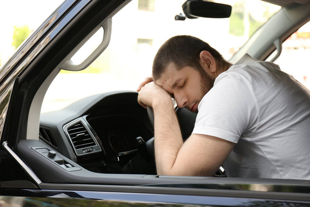 Tired man sleeping on steering wheel in his car - Foto, Imagem