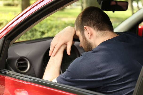 Tired man sleeping on steering wheel in his car - Фото, изображение