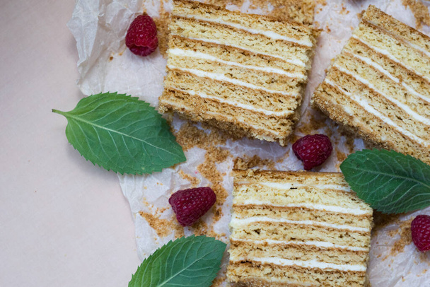 Beautiful close-up of honey cake on a paper with mint and raspberries. horizontal - Fotoğraf, Görsel