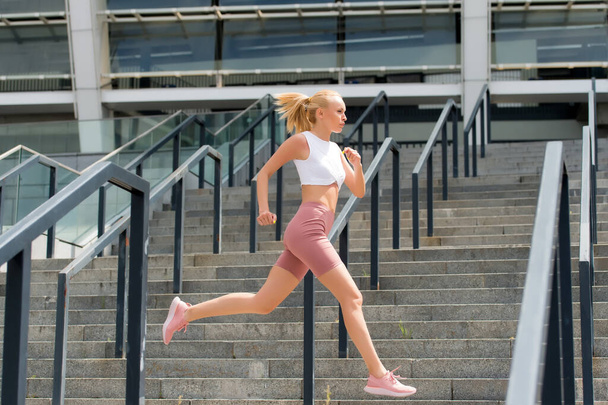 Run like beast, look like beauty. Energetic woman run at stadium. Fast run. Fit athlete in sexy sportswear. Athletic female runner. Training and workout. Fitness and sport motivation. Run some more - Foto, imagen