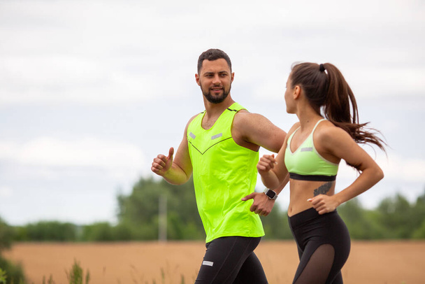 Sports guy and girl in stylish sports clothes running in nature, photo for blog and ad of sport and healthy lifestyle - Фото, изображение