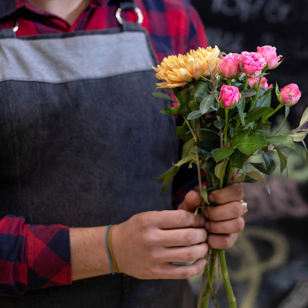 Virágárus férfi virágcsokrot készít a boltban - Fotó, kép