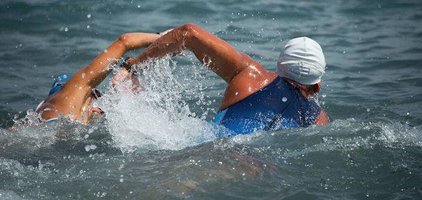 Пловцы триатлона взбираются на воду два пловца в гонках по триатлону
 - Фото, изображение