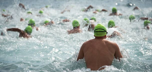 Competidores nadando en aguas abiertas al comienzo del triatlón - Foto, Imagen