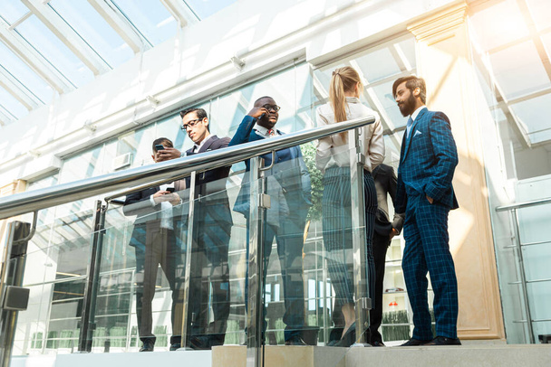 young business people are standing and talking on the background of glass offices. Corporate businessteam and manager in a meeting. - Photo, Image