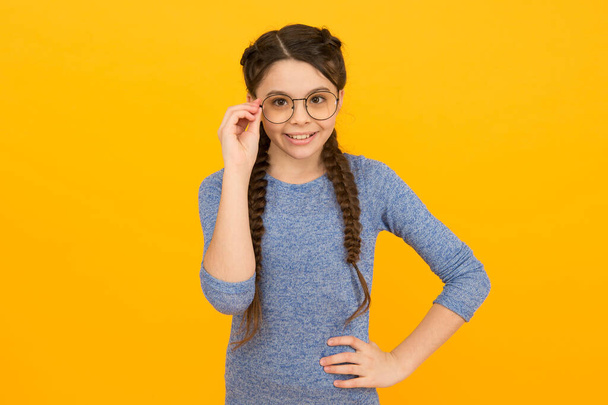 Fashion eyewear and trendy eyeglasses. Happy fashionista yellow background. Little child with long hair braids. Casual style. Beauty and fashion. Fashion accessory. Fashion eyewear you want to wear - Zdjęcie, obraz