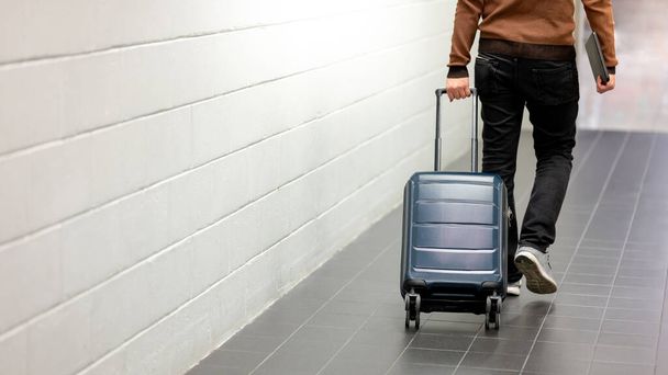 Matkavakuutuksen käsite. Mies turisti kuljettaa matkalaukku matkatavarat ja digitaalinen tabletti kävely lentokentän terminaali. - Valokuva, kuva