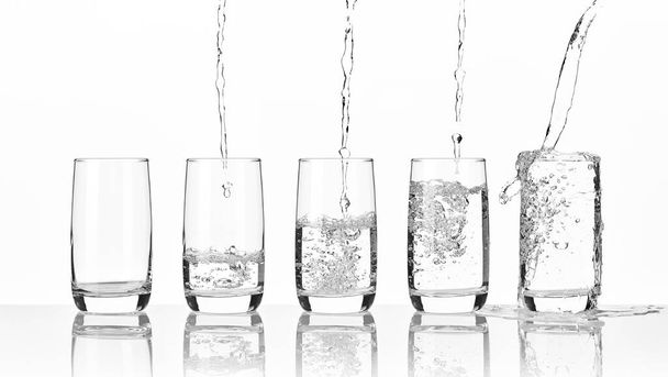Five glasses of pouring water on a light background - Foto, Imagen