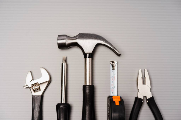Composición plana de un conjunto de herramientas, incluyendo martillo, alicates, llave inglesa, destornilladores y cinta métrica
 - Foto, Imagen