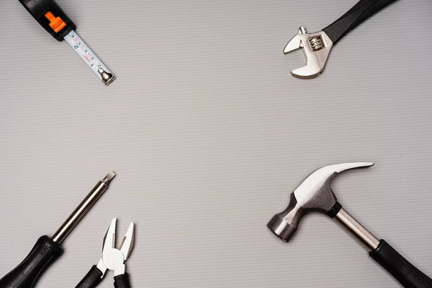 Composição de colocação plana de um conjunto de ferramentas, incluindo martelo, alicate, chave, chaves de fenda e fita métrica
 - Foto, Imagem