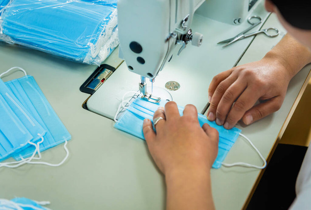 Woman sew the facial medical at sewing machine. Coronavirus pandemia. - Foto, imagen