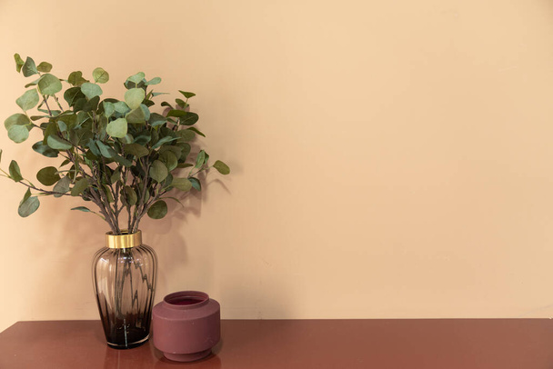 Ницца искусственное растение в стеклянной вазе с красной керамической вазой установки на пустой красный стол в минимальном современном стиле квартира / жилой интерьер концепции / копировальное пространство
 - Фото, изображение