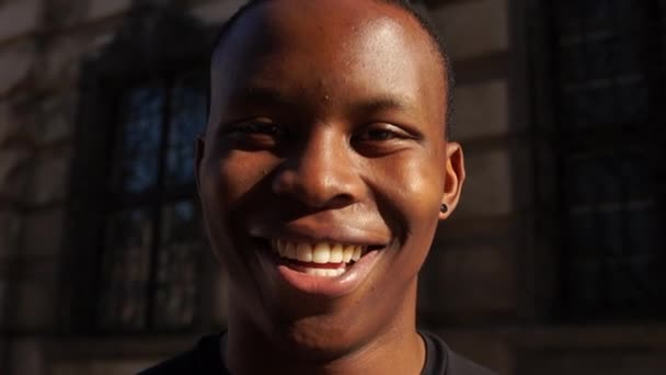 Black man smiles and wonders while looking at the camera. Portrait of a young african american man on city street. Happy people concept, stop rasicm - Záběry, video