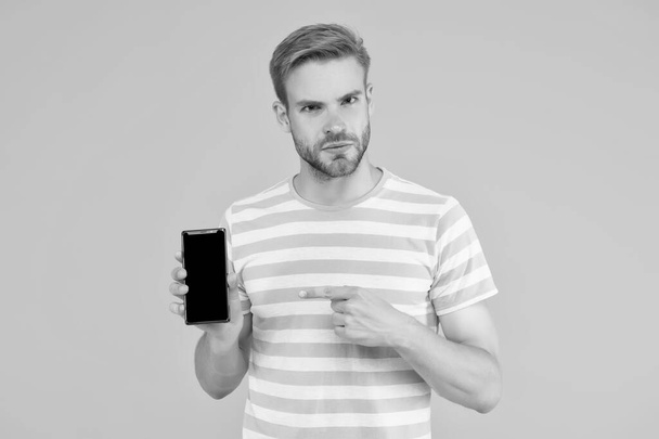 Download and start play. Man pointing at smartphone. Pointing gesture. Index finger pointing. Pointing for advertising. Digital technology. Mobile services. Free internet. Application smartphone - Fotoğraf, Görsel