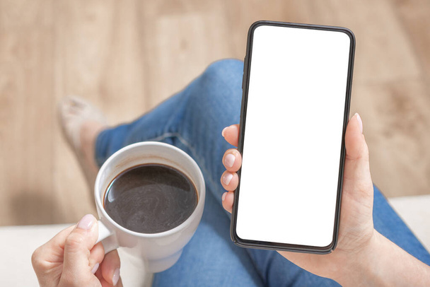 Mockup image of woman holding black mobile phone with blank white screen in cafe. Cropped shot view of woman's hands holding smart phone with blank copy space screen for your text message or information content, female reading text message on cell te - Fotoğraf, Görsel
