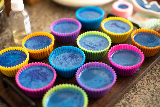 Colorful silicon cupcake molds on wooden coard filled with liquid soap for a home made hobby of melt and pour soapmaking - Photo, Image