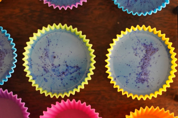 Moules à cupcake en silicium coloré sur une barde en bois remplie de savon liquide pour un passe-temps fait maison de fusion et de savonnerie - Photo, image