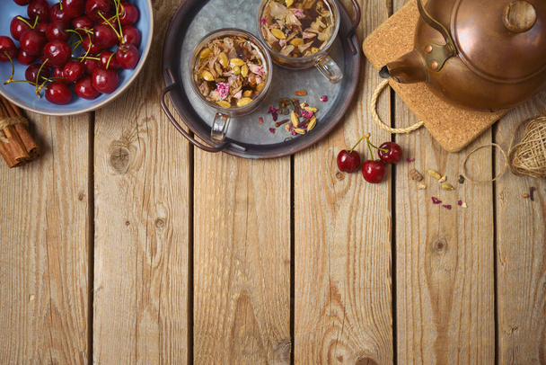 Dry herbal tea with fresh cherries on wooden table. Healthy lifestyle concept. Top view from above - Fotografie, Obrázek
